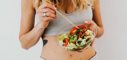Woman in sports attire enjoys a fresh, nutritious salad, embodying a healthy lifestyle.