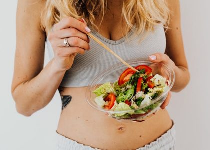 Woman in sports attire enjoys a fresh, nutritious salad, embodying a healthy lifestyle.