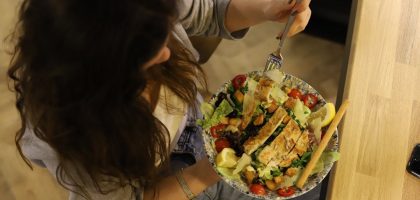 Overhead view of a woman eating a chicken salad balancing health with deliciousness.