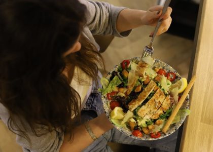 Overhead view of a woman eating a chicken salad balancing health with deliciousness.